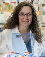 a woman in a whitecoat smiling for a portrait